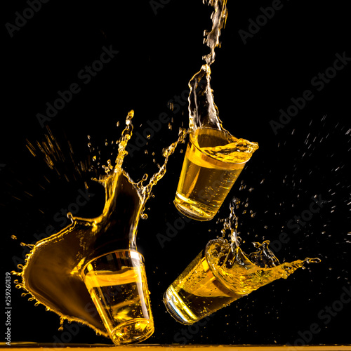Three golden tequila shots crashing down and splashing