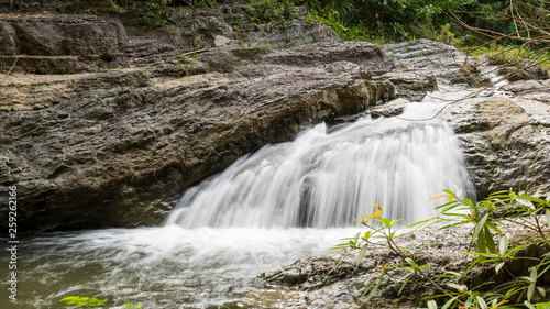 Waterfall stream surrounded by green tropical green forest 