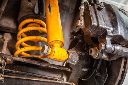 Extreme closeup of yellow shock absorber underneath a car