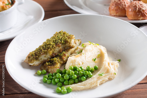 Fried fish with herbs and spices with mashed potatoes and green peas