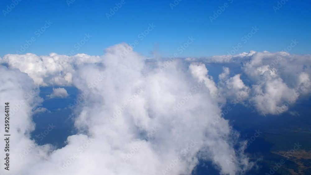 Above the clouds, flying in the air. View of clouds through airplane window.