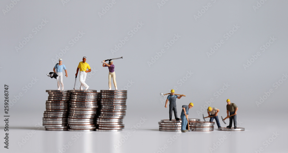 Miniature people standing on a pile of coins. A concept of income disparity.