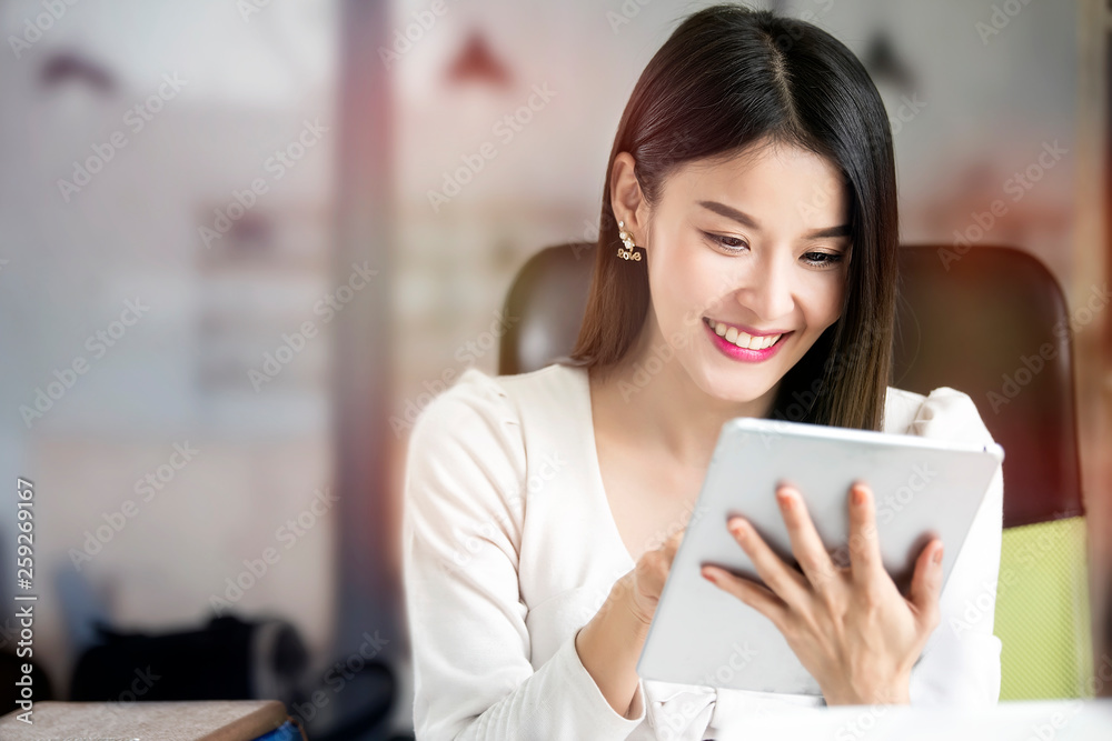 Beautiful woman using tablet while sitting at office desk. Beautiful woman using tablet while sitting at office desk.