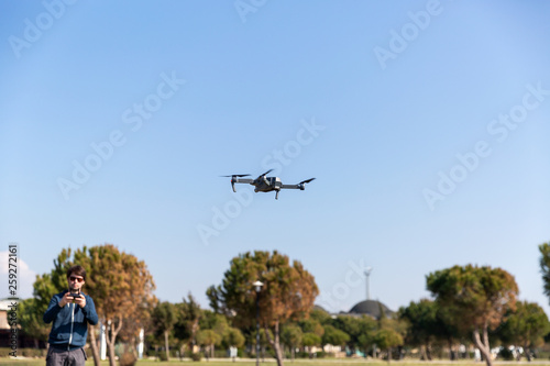 A man piloting a drone in the park in spring-summer time