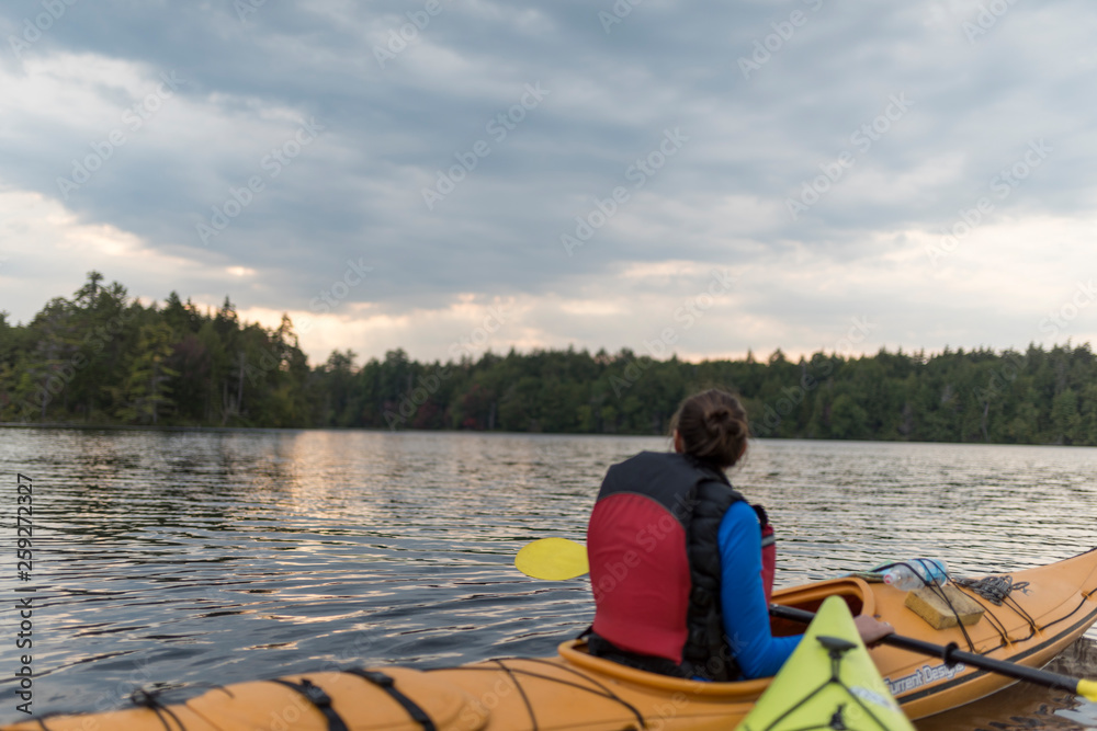 a woman views something in the distance while inside of a kayak on a lake a woman views something in the distance while inside of a kayak on a lake