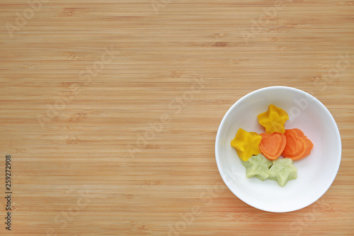 frozen mashed baby food homemade in white ceramic bowl on wooden board.