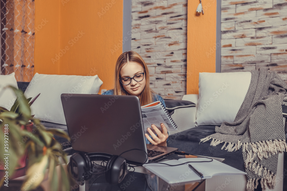 Fototapeta premium Girl sitting on the floor and studying with a laptop before the exam