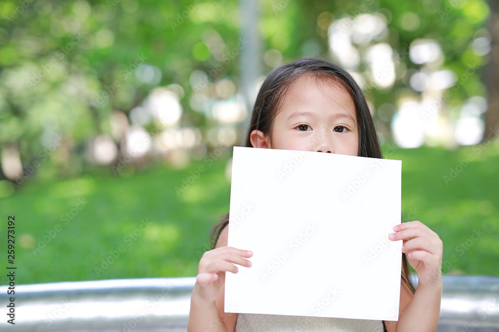 Adorable little Asian child girl holding up a blank white paper. Adorable little Asian child girl holding up a blank white paper.