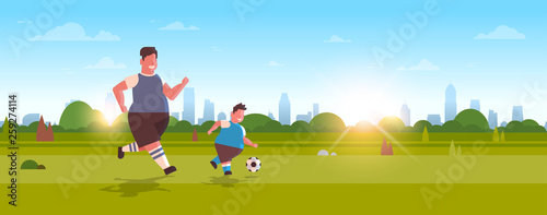 fat overweight father with obese son playing football over size family having fun on green lawn at park weight loss activity concept horizontal landscape background full length