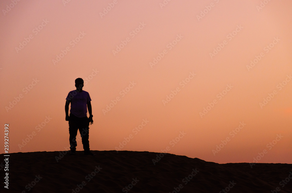 silhouette of lonely man in beautiful evening in desert