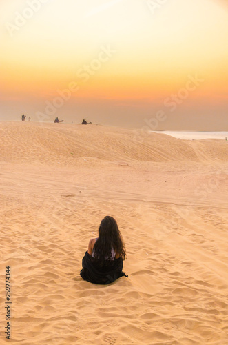 back view of girl sitting on desert in beautiful evening