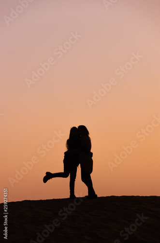 silhouette of two friends in beautiful evening in desert