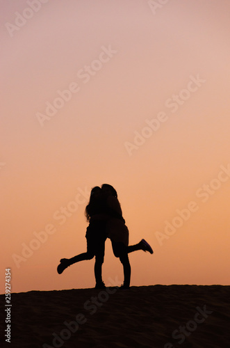 silhouette of two friends in beautiful evening in desert