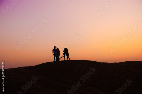 silhouette of five friends in beautiful evening in desert