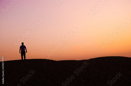 silhouette of lonely man in beautiful evening in desert