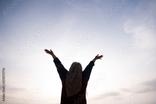Unidentified silhouette happiness and joyful woman girl rise hand up during oceanview on blue sky background - Image