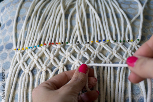 Manos de mujer trabajando tejido de nudos. Macramé