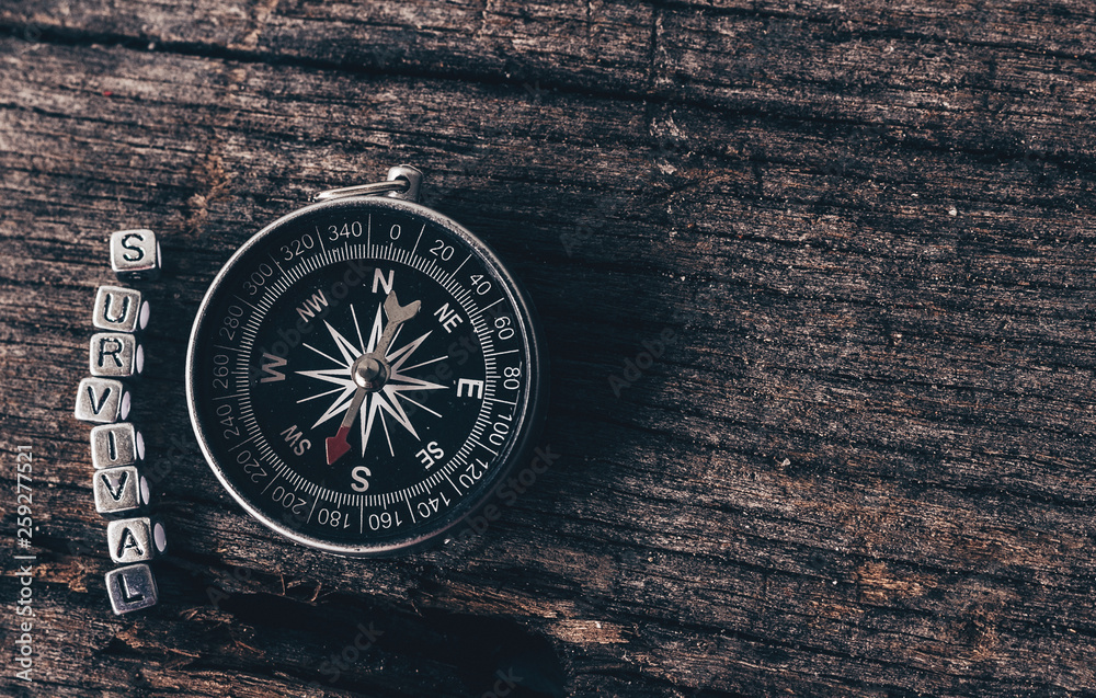Compass on wood deck with blocks of letters making the word survival. Compass on wood deck with blocks of letters making the word survival.
