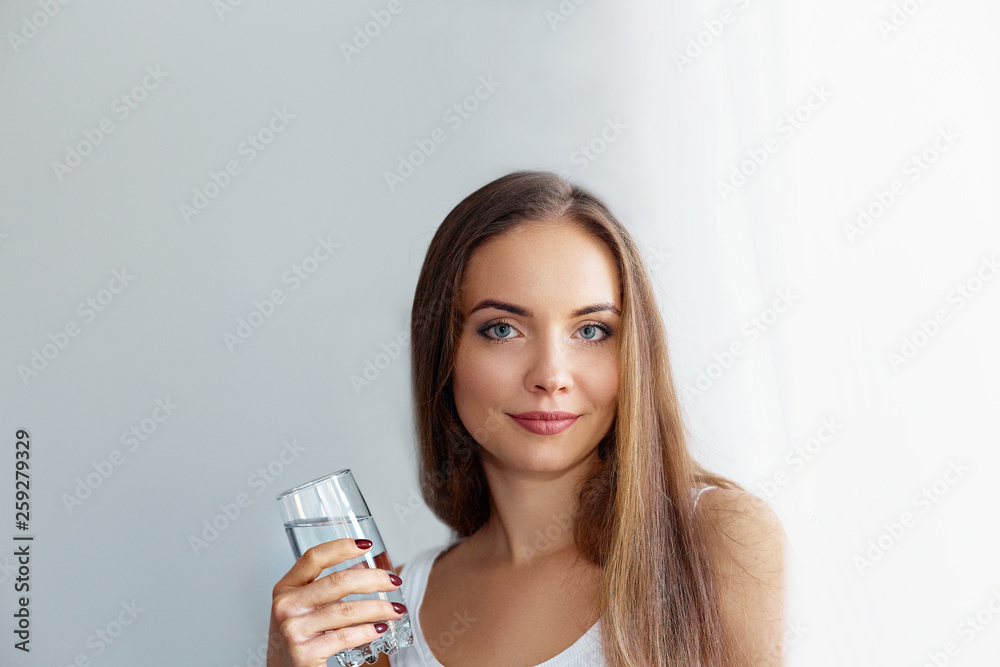 Healthy lifestyle.Young woman drinking from a glass of  fresh water. Healthcare. Drinks. Portrait of happy smiling female model holding transparent glass. Health,Beauty,Diet concept. Healthy eating.
