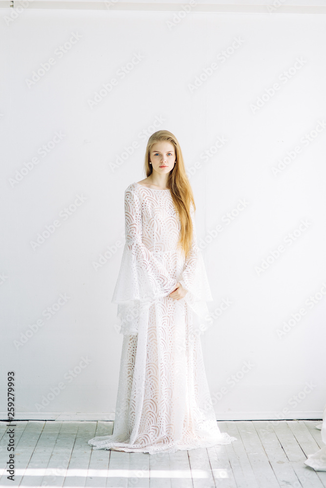 Beautiful bride on a white minimalistic background. Wedding preparations in fine art.