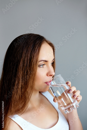 Healthy lifestyle.Young woman drinking from a glass of fresh water. Healthcare. Drinks. Portrait of happy smiling female model holding transparent glass. Health,Beauty,Diet concept. Healthy eating.