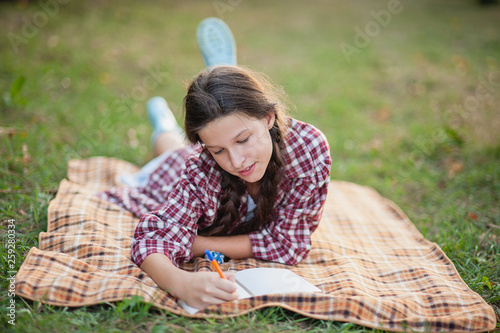 The girl sitting under the tree and wrote in Notepad photo