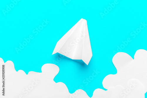 Flying paper plane in the clouds on a blue background. Concept of flight  travel  transfer