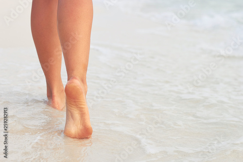 Сlose up of woman leg on the beach. Woman feet walking on the sand. Foot female.Skin Care.