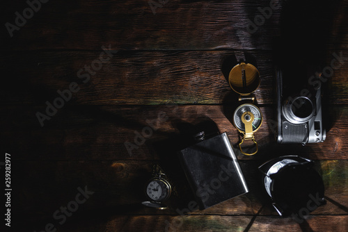 Travel or adventure flat lay background with a copy space. A flashlight, compass, photo camera, pocket watch and water flask on a tourist table.