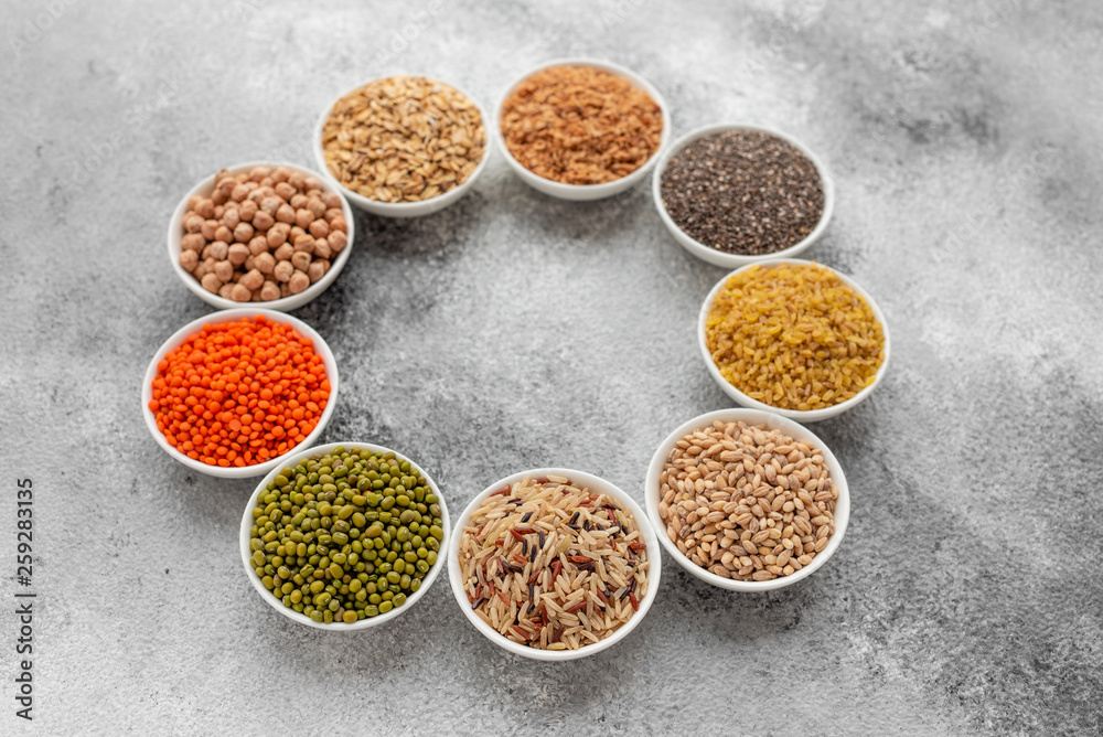 Variations of porridges and bean in white saucers on a gray concrete background