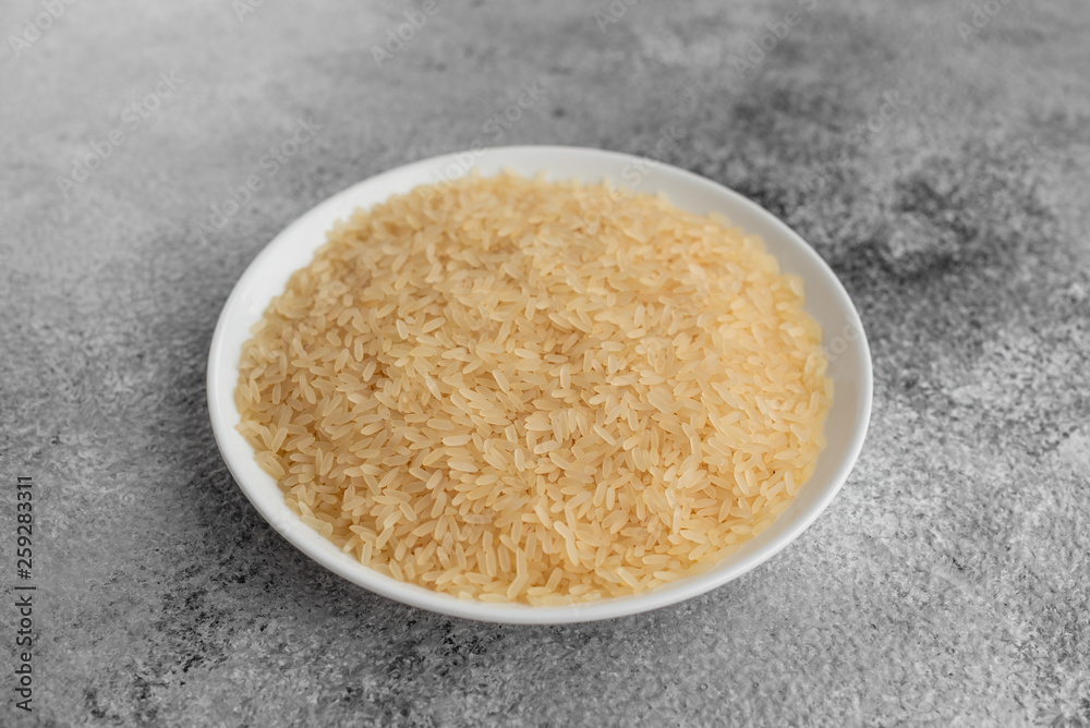 Rice in a white saucer on a gray concrete background Rice in a white saucer on a gray concrete background
