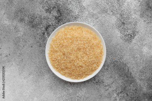 Rice in a white saucer on a gray concrete background