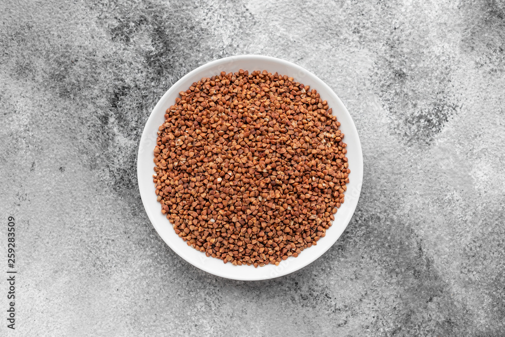Buckwheat cereal in a white saucer on a gray concrete background Buckwheat cereal in a white saucer on a gray concrete background