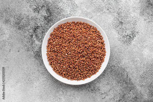 Buckwheat cereal in a white saucer on a gray concrete background