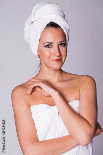 Young woman without makeup in a bath towel on her head, isolated on white