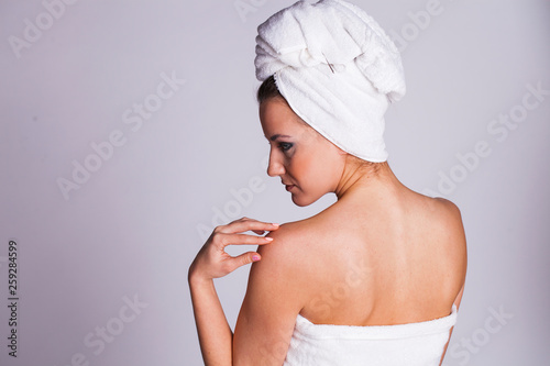 Young woman without makeup in a bath towel on her head, isolated on white