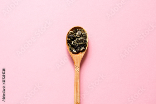 Biluochun. Chinese leaf green tea in a spoon on a pink background. Top view and copy space. photo