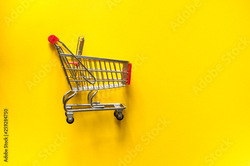 Top view and copy space. Shopping cart trolley on a yellow background.