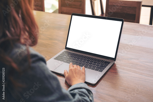 Mockup image of a woman using and touching on laptop touchpad with blank white desktop screen on wooden table