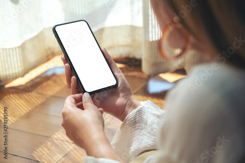 Фотография Mockup image of a woman holding and using black mobile phone with blank desktop