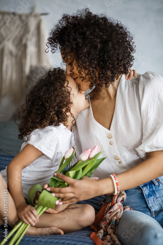 Happy Women's Day. Mom and daughter tulips. Mom and girl are smiling with braces of African-American appearance