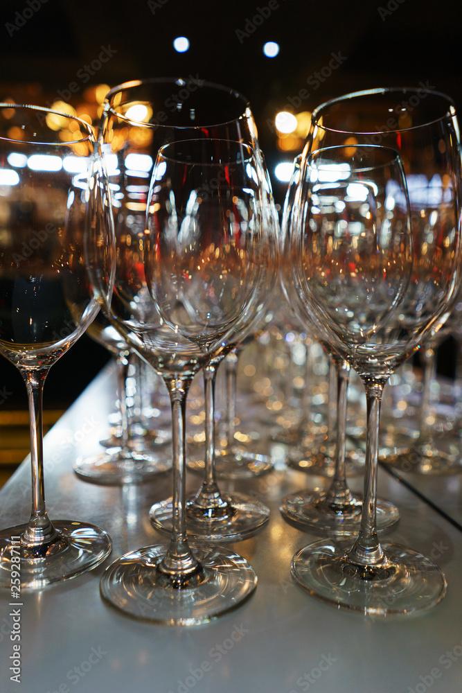 row of transparent clean wine glasses and champagne on a rack in a bar or restaurant prepared for guests of festive events. 