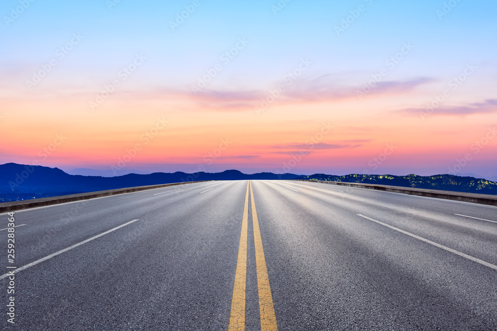 Straight asphalt road and beautiful mountain nature landscape at sunset
