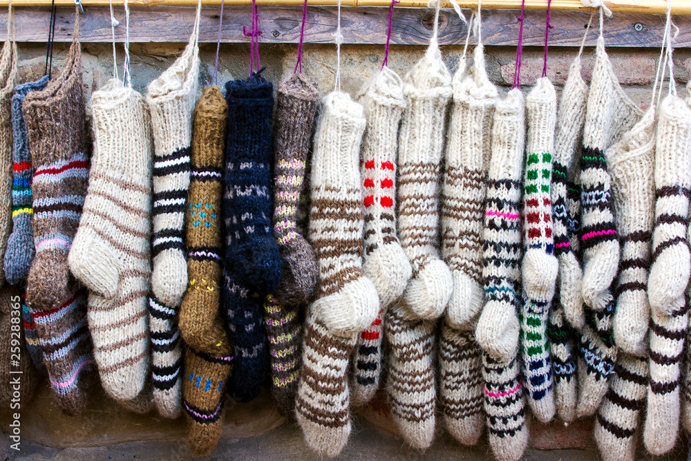 New knitted wool socks of different colors and ornaments hanging in a row