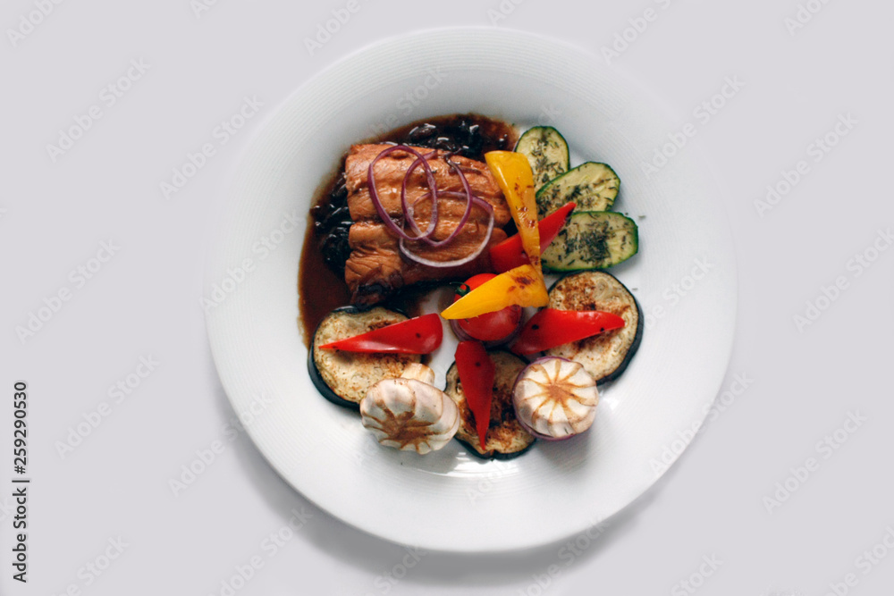 Grilled salmon fillet and grilled vegetables on a white porcelain plate. Grilled salmon fillet and grilled vegetables on a white porcelain plate.