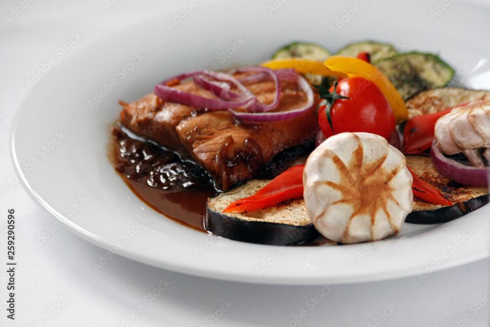 Grilled salmon fillet and grilled vegetables on a white porcelain plate. Grilled salmon fillet and grilled vegetables on a white porcelain plate.