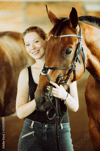 Woman hugging brown horse in stable