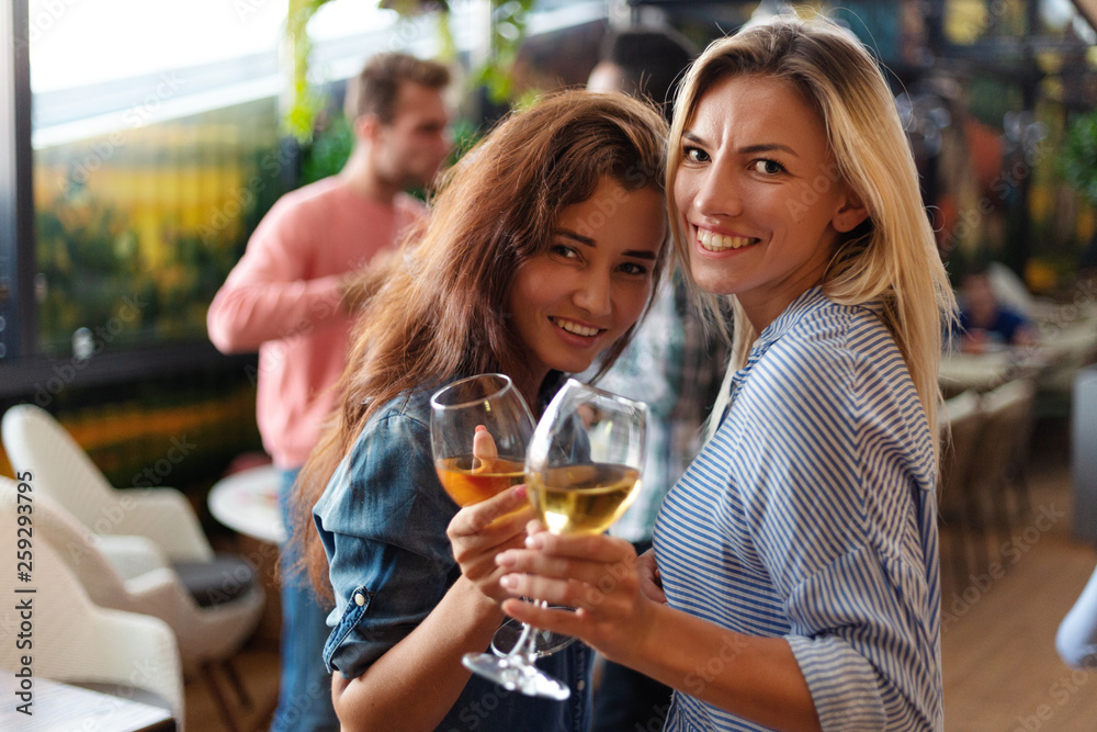 Φωτογραφία Two beautiful women posing with glasses of wine and smiling at camera at party i