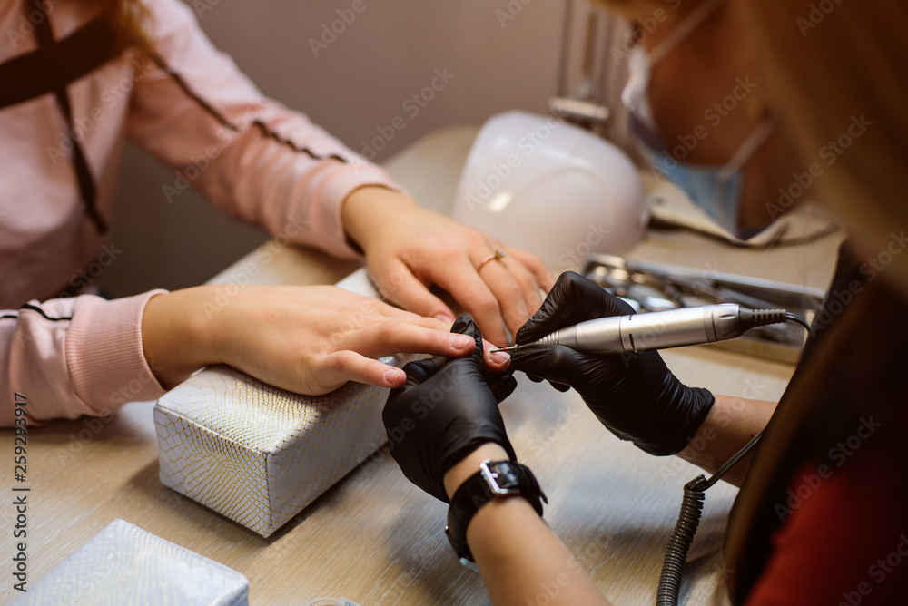 Manicure process, cleaning of woman nails by a milling cutter