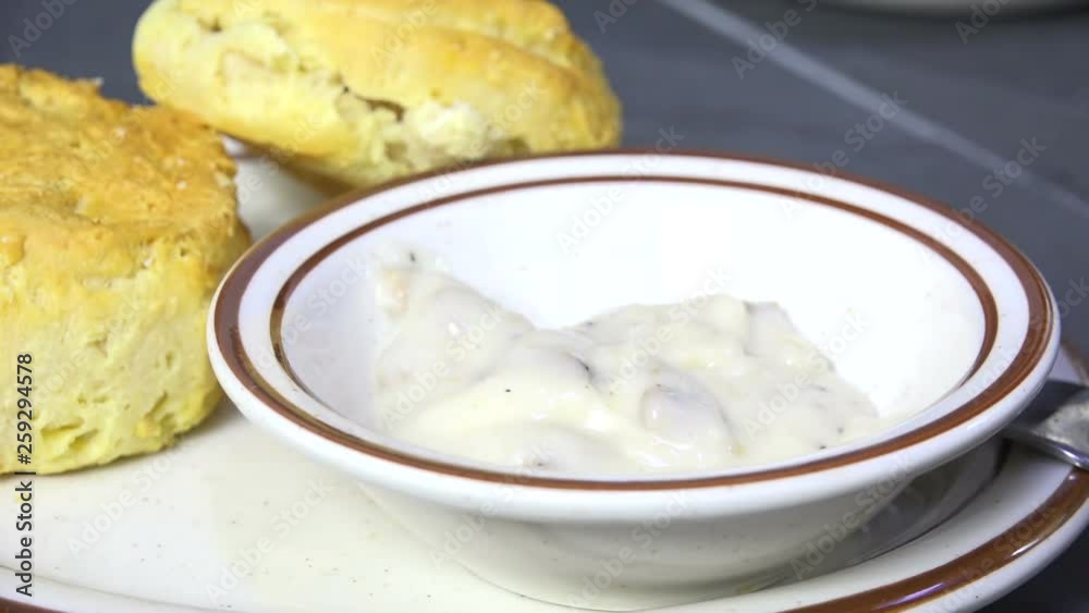 Spooning country gravy with sausage into a bowl Spooning country gravy with sausage into a bowl